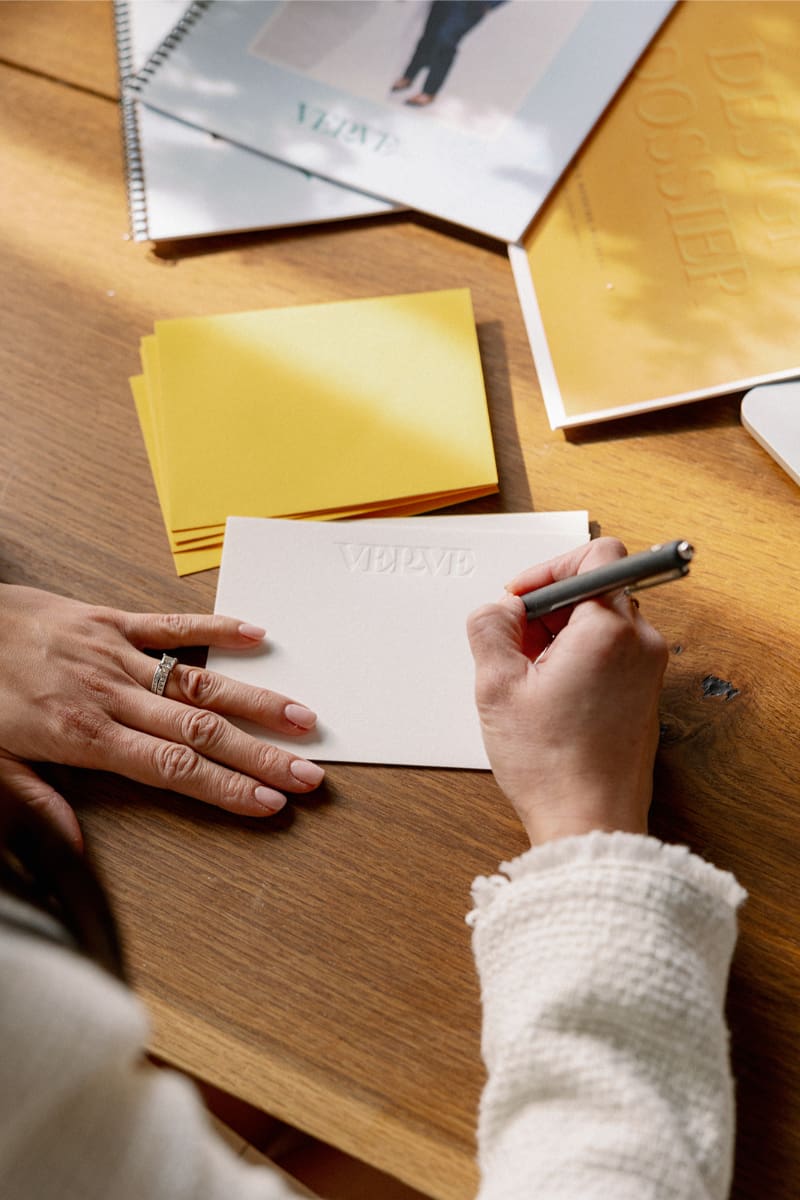 Desirée Adams sits down at desk to write a note to wrap up the first season of her wedding planner podcast - The Planner's Edit.